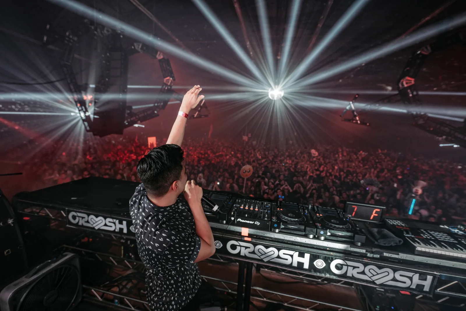 Ravell raising his arm to the crowd under stage lights
